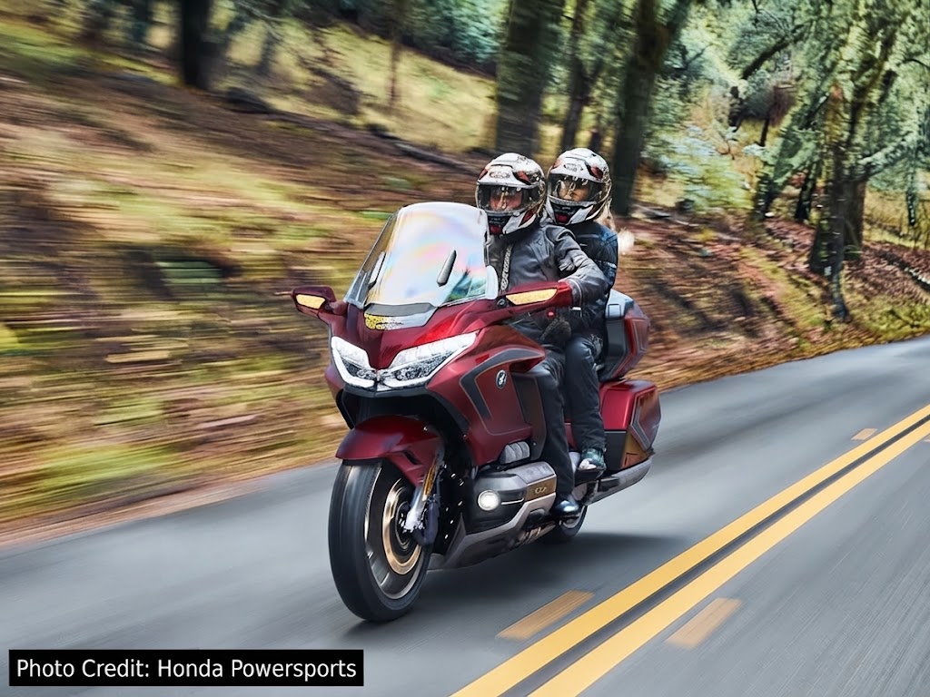 Honda Gold Wing Tour luxury touring motorcycle with two riders on a scenic road.